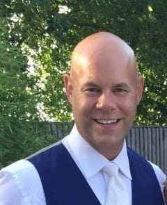 A bald man with a white shirt and tie